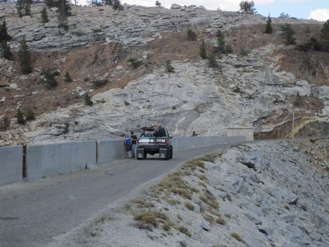 1989 Ford Bronco - A dark green Ford Bronco is parked on a mountain road with two people standing nearby.