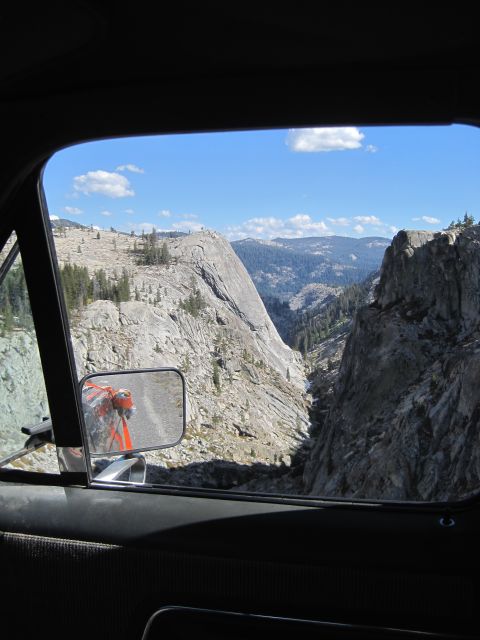1989 Ford Bronco - View from inside a vehicle looking out at a vast mountain landscape, with the side mirror reflecting an orange object.