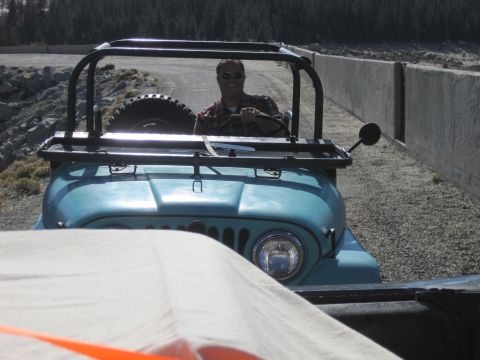 1989 Ford Bronco - A man smiles while driving a light blue Jeep CJ on a gravel road.