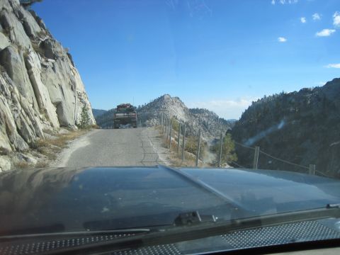 1989 Ford Bronco - A truck drives up a winding mountain road with steep cliffs and a clear blue sky.