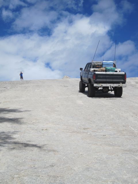 1989 Ford Bronco - Modified pickup truck with gear loaded in the bed sits on a dusty hill.