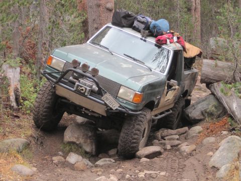 1989 Ford Bronco - This 1989 Ford Bronco navigates a challenging rocky off-road trail, carrying camping equipment.