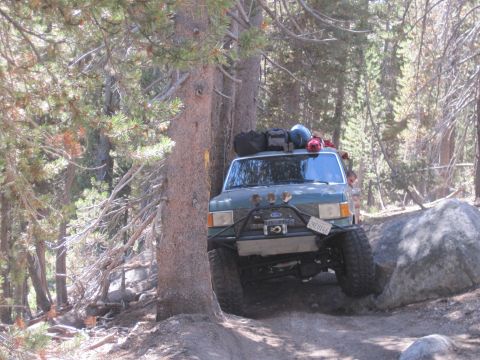 1989 Ford Bronco - Modified 1989 Ford Bronco tackles a challenging off-road path in a wooded area.