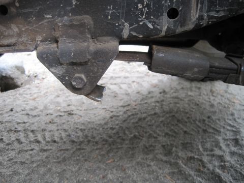 1989 Ford Bronco - A close-up view of a damaged suspension component on a vehicle, showing wear and tear.