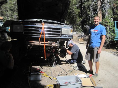 1989 Ford Bronco - Two men work on the front end of a Ford truck outdoors, with another vehicle in the background.