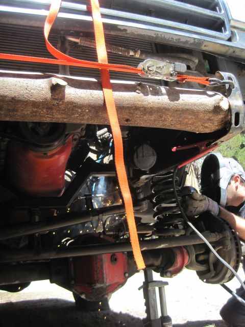 1989 Ford Bronco - A person welds on the undercarriage of a vehicle, which is secured by orange straps.