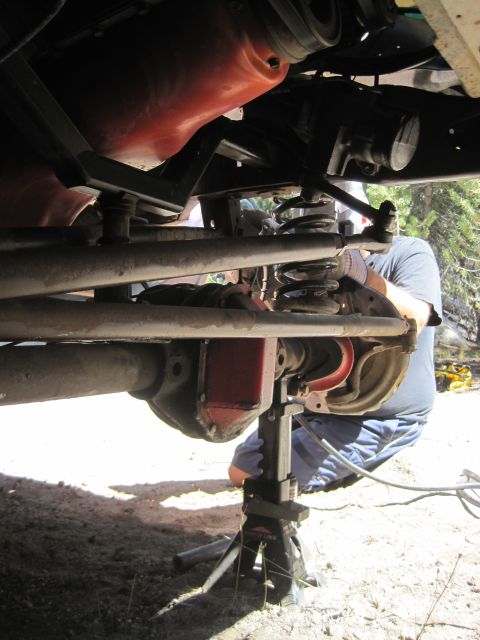 1989 Ford Bronco - Vehicle suspension work in progress, with a person attending to the axle and springs.