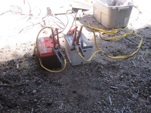 1989 Ford Bronco - Two car batteries are connected with jumper cables, possibly for charging or jump-starting.
