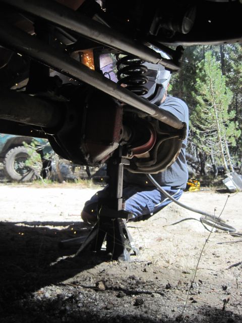 1989 Ford Bronco - Welding repairs being performed on a vehicle's suspension system outdoors.