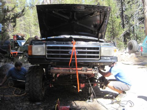 1989 Ford Bronco - A black Ford truck, likely from the late 1980s, is being worked on outdoors with its hood up.