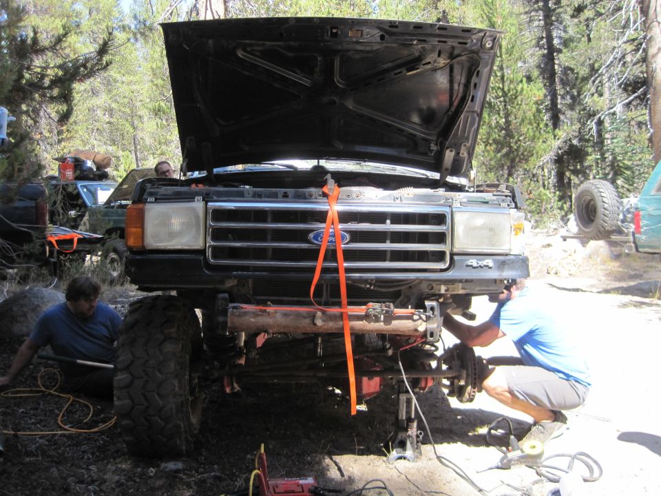 Front view of a black Ford truck with hood open, undergoing repairs. "4x4" visible on fender
