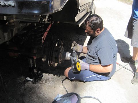 1989 Ford Bronco - A mechanic works on the suspension of a 4x4 vehicle, possibly a Jeep or similar off-road SUV.