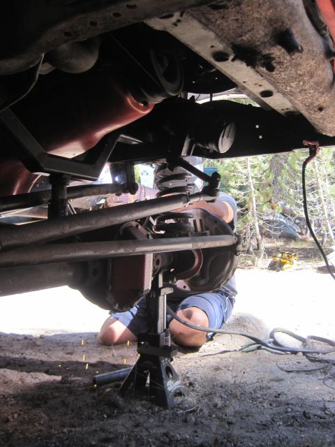 1989 Ford Bronco - A person welds the undercarriage of a vehicle supported by jack stands in an outdoor setting.