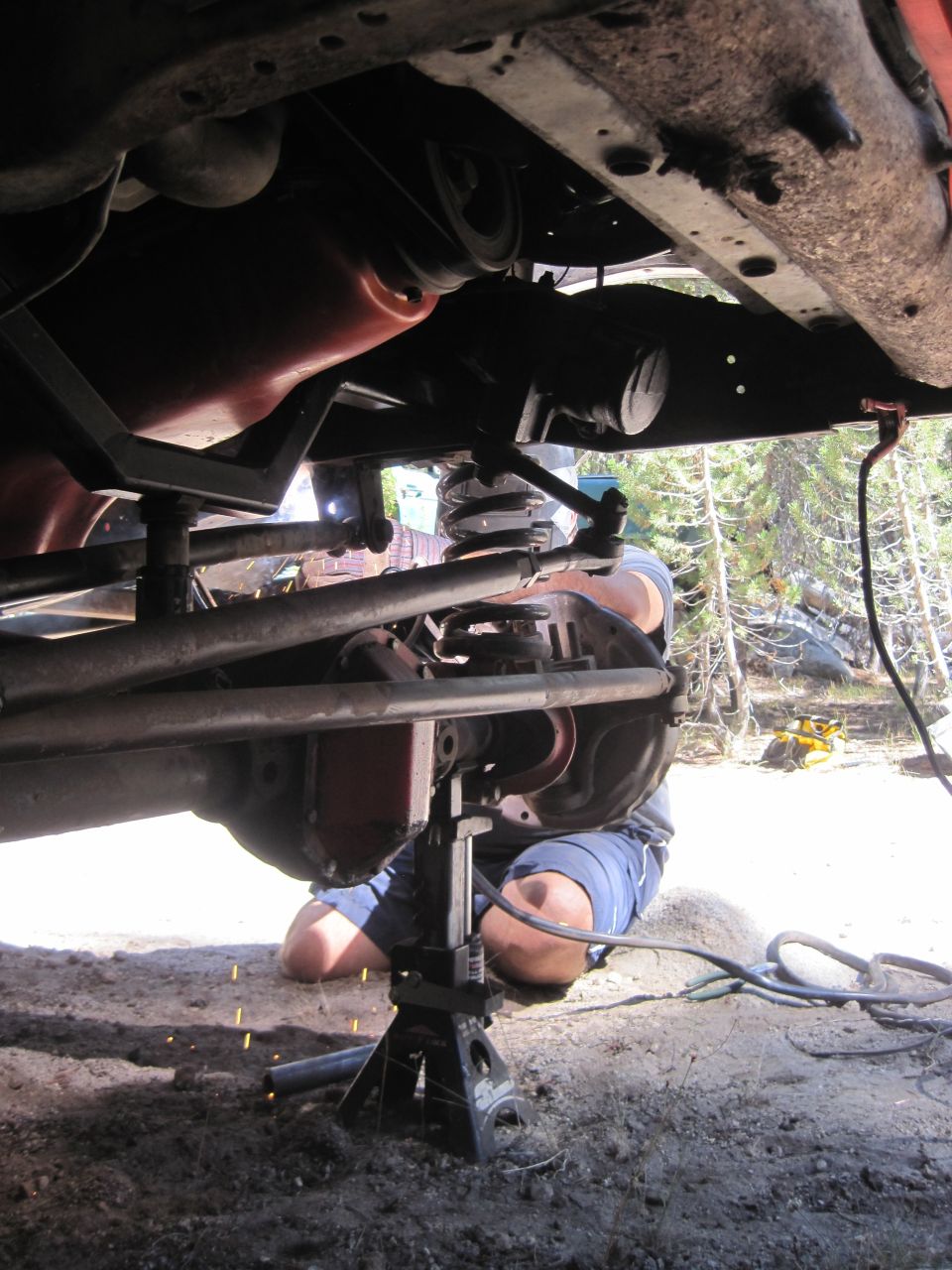 Underbody of a vehicle on jack stands with a person welding
