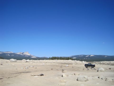 1989 Ford Bronco - A black Ford Bronco is parked in a vast, arid landscape under a clear blue sky.