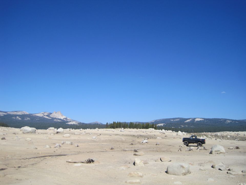 Black Ford Bronco parked in a dry, rocky, open field with mountains in the background