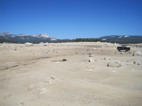 1989 Ford Bronco - A black pickup truck is parked in a desolate, rocky landscape under a clear blue sky.