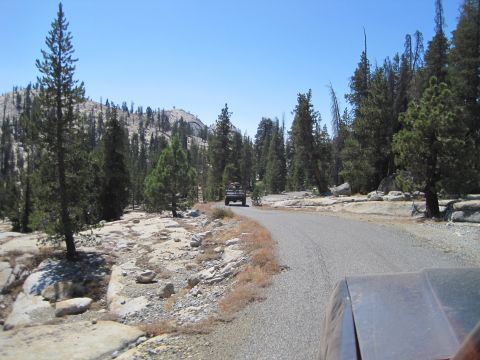 1989 Ford Bronco - Driving on a mountain road with another truck in front, surrounded by trees and rocks.