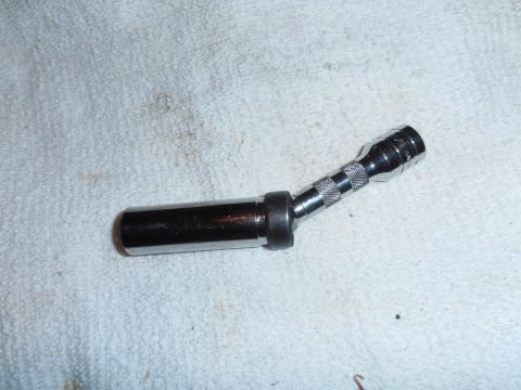 1990 Ford Bronco - A spark plug socket wrench with a knurled grip and an angled head rests on a white cloth surface.