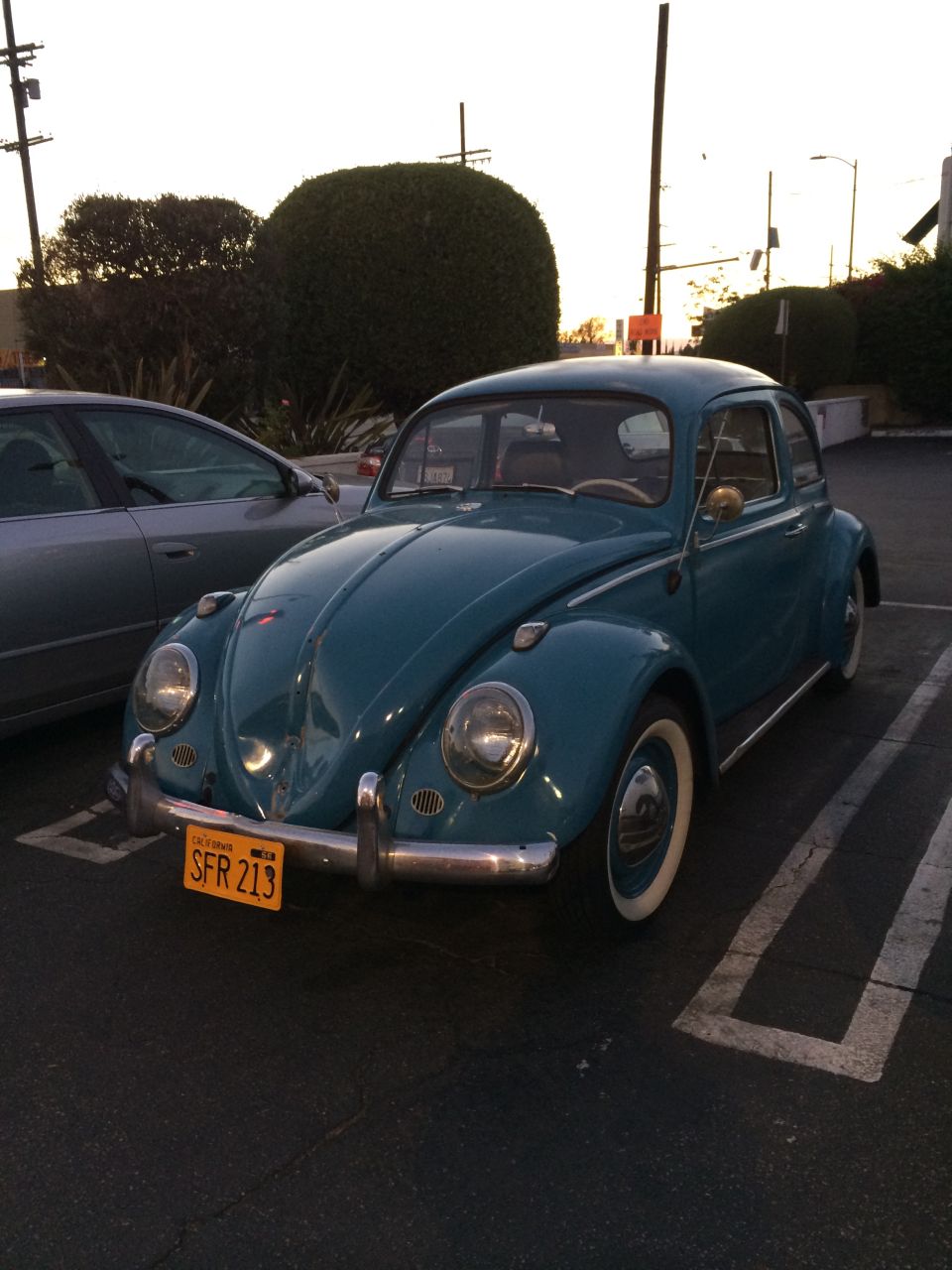 Teal Volkswagen Beetle parked in a lot, California license plate SFR 213 visible