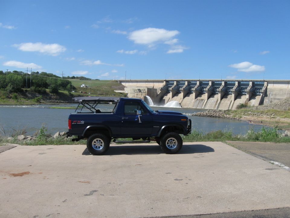 Blue Ford Bronco parked in front of a dam with water flowing