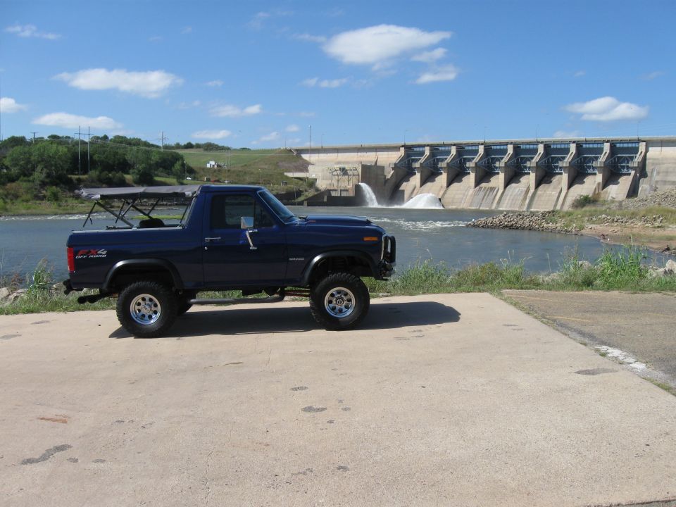Blue 4x4 SUV parked by a dam, circa 1980