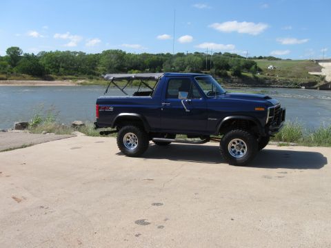 1982 Ford Bronco - This 1982 Ford Bronco is parked near a body of water with a dam in the background.