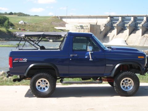 1982 Ford Bronco - This blue 1982 Ford Bronco features FX4 off-road badging and a removable soft top, seen here with a dam in the background.