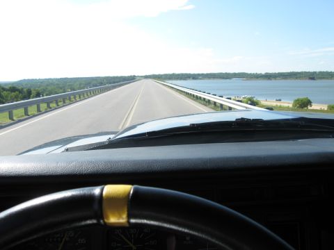 1982 Ford Bronco - View from inside a vehicle as it drives across a bridge with a body of water to the right.