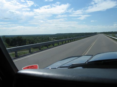 1982 Ford Bronco - View from inside a vehicle driving on a highway, with a red sticker visible on the windshield.