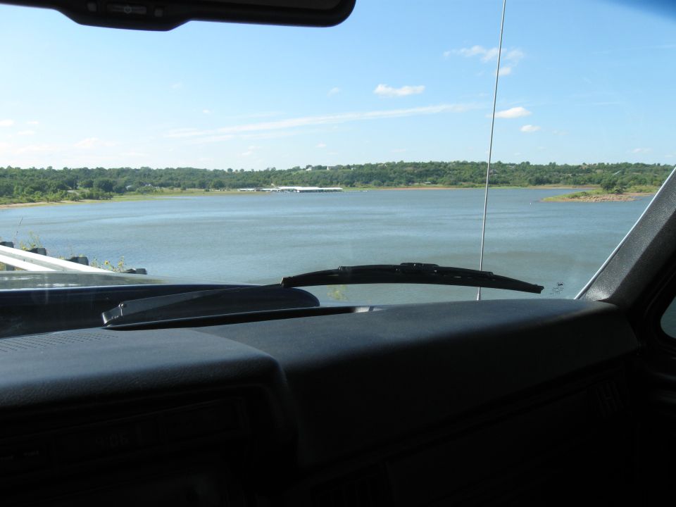 Dashboard and windshield view of a lake and distant treeline