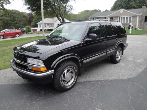 2001 Ford Crown Victoria - Black SUV parked on a paved driveway in front of a residential house.