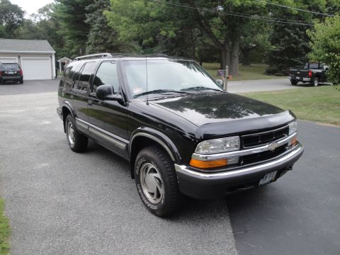 2001 Ford Crown Victoria - This black SUV is parked in a driveway with a garage and another vehicle in the background.