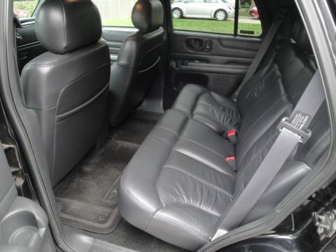 2001 Ford Crown Victoria - The interior of a black SUV shows the rear leather seats and door panel, with a glimpse of the exterior through the window.