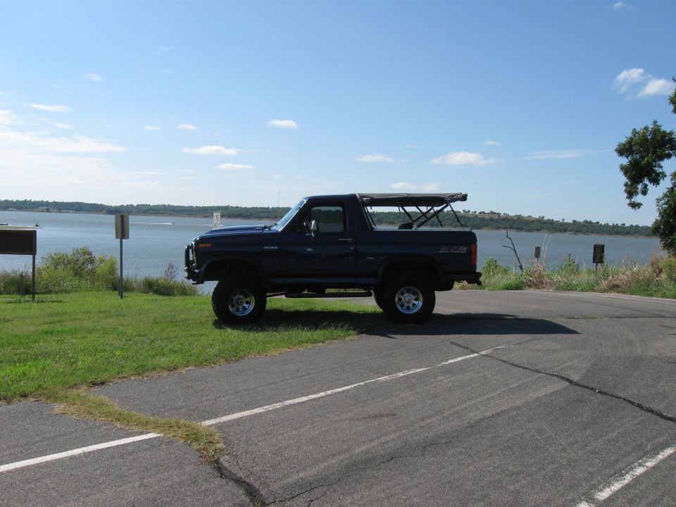 Dark blue Ford Bronco parked by a lake