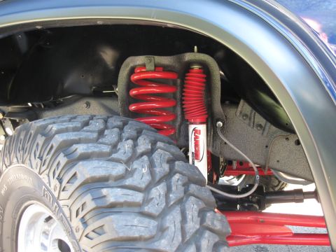 1982 Ford Bronco - The front suspension system of a vehicle, including a tire and shock absorber, is shown in a close-up view.