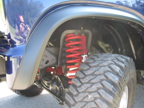 1982 Ford Bronco - Front suspension detail with red coil springs visible on a blue vehicle.