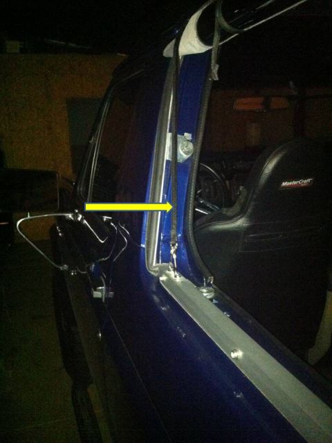 1982 Ford Bronco - Close-up of a blue vehicle's interior door frame, with a yellow arrow highlighting a cable assembly.