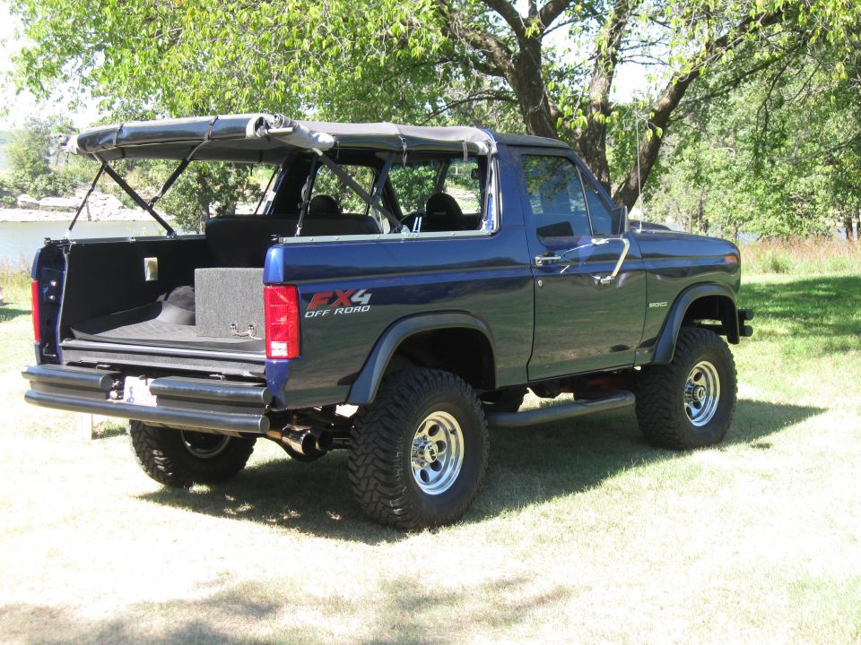 1982 Ford Bronco with soft top removed, parked on grass near water