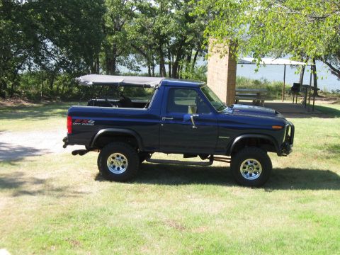 1982 Ford Bronco - This 1982 Ford Bronco 4x4 features a removable soft top and is parked in a grassy area near a body of water.