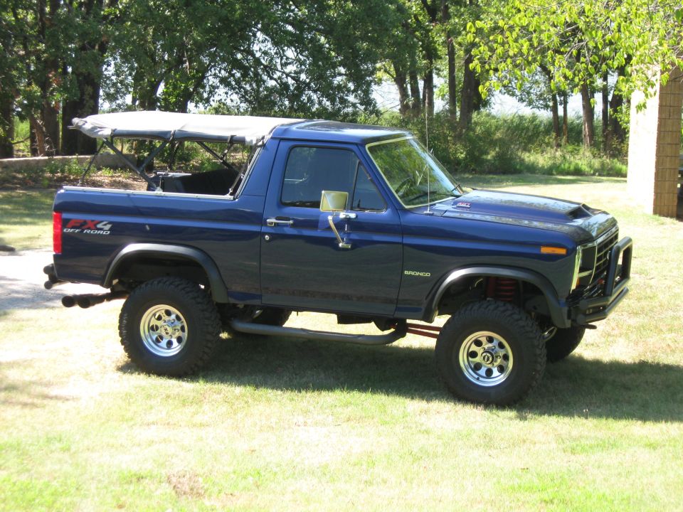 1982 Ford Bronco with a blue exterior and a removable soft top, lifted with off-road tires