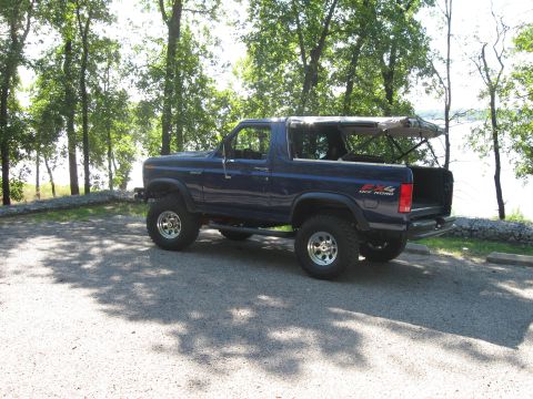 1982 Ford Bronco - This 1982 Ford Bronco is parked outdoors with its soft top partially open.
