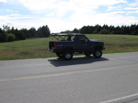 1982 Ford Bronco - 1982 Ford Bronco with its top removed, parked on the shoulder of a rural road.