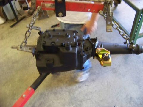 1974 Dodge Challenger - A vehicle's transmission and rear axle assembly are suspended by chains and a red support stand.