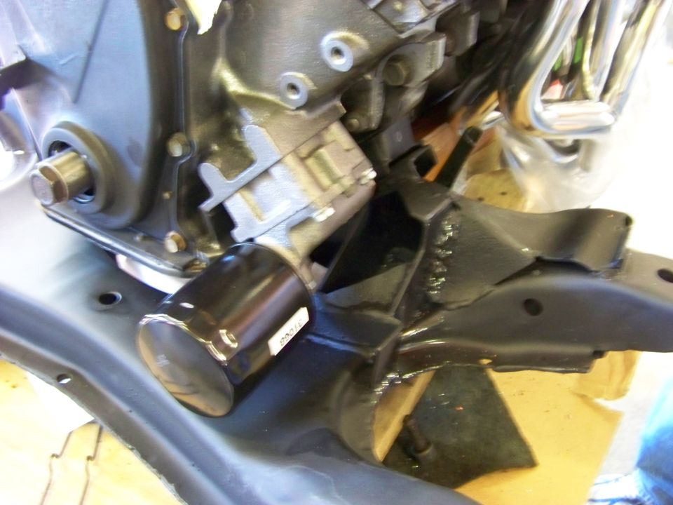 Black oil filter attached to engine block with metal bracket