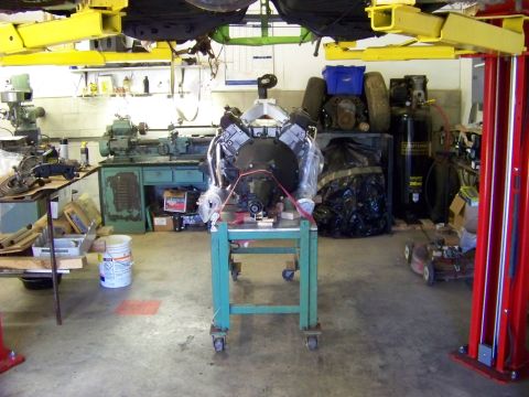 1974 Dodge Challenger - Engine assembly on a stand in a workshop, surrounded by machinery and tools.