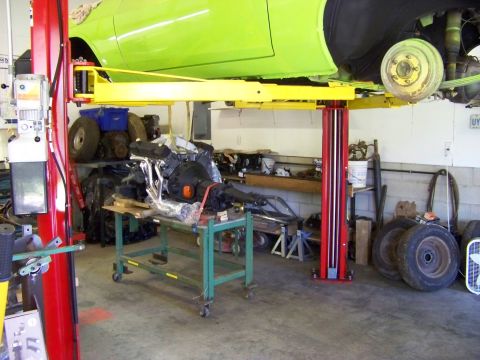 1974 Dodge Challenger - A lime green 1974 Dodge Challenger is elevated on a lift, revealing its underside and removed engine.