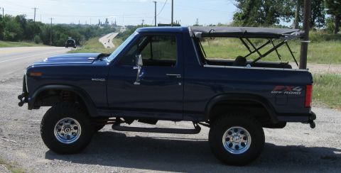 1982 Ford Bronco - Side view of a blue 1982 Ford Bronco with a soft top and FX4 Off Road decal.