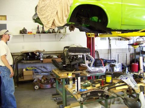 1974 Dodge Challenger - Engine and car parts are visible in a garage setting with a vehicle lifted for work.
