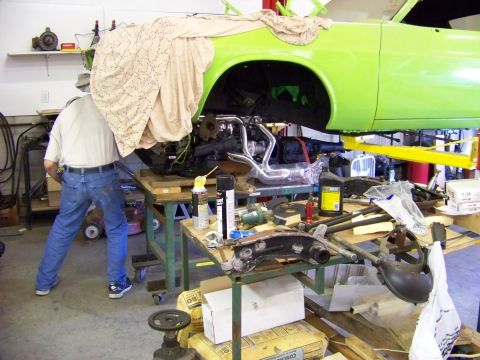 1974 Dodge Challenger - Mechanic works on the engine bay of a 1974 Dodge Challenger undergoing repairs.
